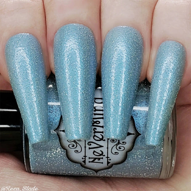 A close-up image of long coffin shaped fingernails painted with a light blue nail polish, featuring a reflective glitter finish, shown without flash