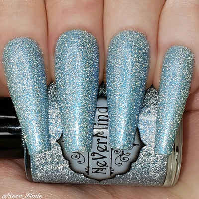 A close-up image of long coffin shaped fingernails painted with a light blue nail polish, featuring a reflective glitter finish.