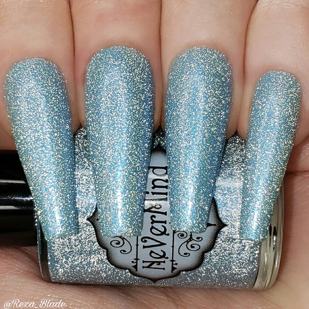 A close-up image of long coffin shaped fingernails painted with a light blue nail polish, featuring a reflective glitter finish.