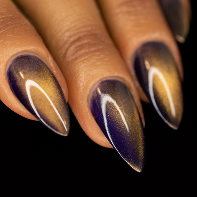A close-up image of a person's fingernails painted with a purple and gold magnetic nail polish, showing a gradient from purple to gold with a magnetic effect.
