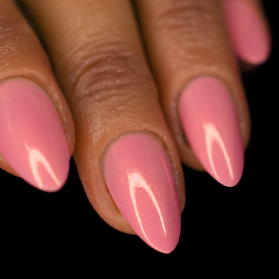 A close-up image of a woman's almond shaped finger nails with pink ballet-style nail polish and a visible gold shimmer.